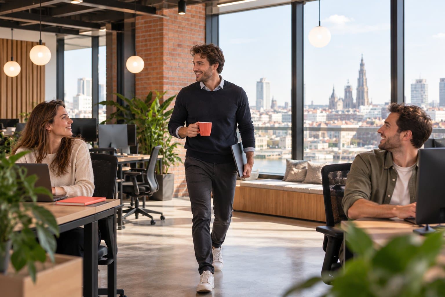 Een recruiter stapt met een koffie en zijn laptop de vloer op, twee collega's begroeten hem