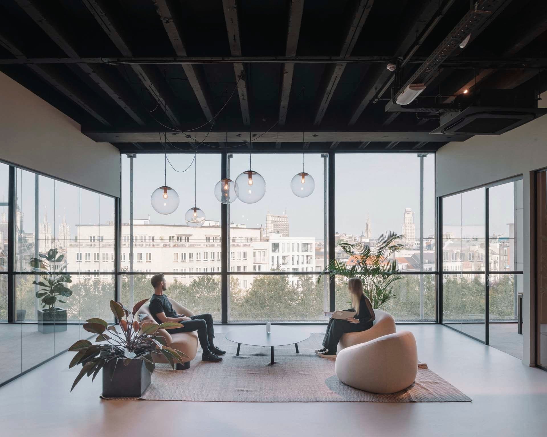 Two recruiters in the lounge of our Antwerp office, with big windows and a view of the city